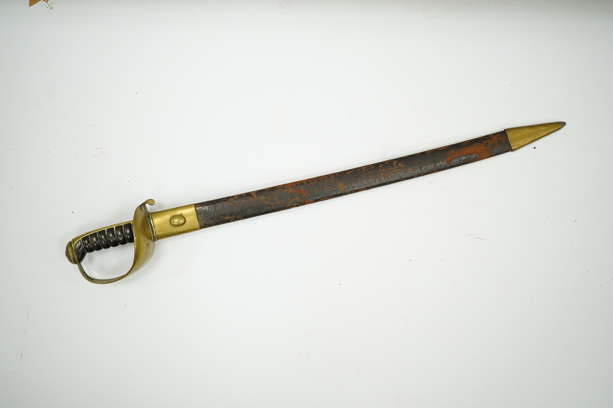 A late 19th century boarding cutlass with plain blade, plain brass guards and mounts, and leather covered grip, in its brass mounted leather scabbard (the chape is an associated replacement). Condition - fair